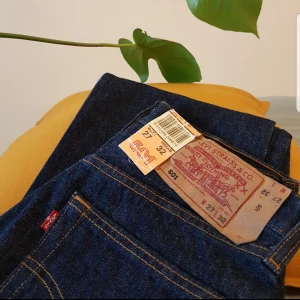  - Helt NYA Levi's 501 i en snygg mörkblå tvätt med orange sömmar! Dösnygga! Tyvärr är W27 för litet för mig och den enda anledningen att jag säljer dem. Klassisk knappgylf, regular/högre i midjan med raka ben. Frakt tillkommer.