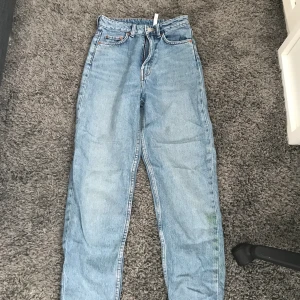 Mom jeans  - Säljer ett par ljusblåa weekdays jeans i modellen Lash. Byxorna har en gräsfläck på bilden som ni kan se men den går att ta bort. Storlek är 24/28.