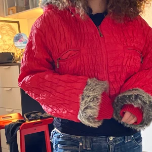 Röd vinterjacka  - En röd vinterjacka med päls på luvan och ärmarna, ganska kort. Kontakta mig för mer info eller bilder