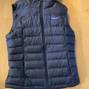 Patagonia väst - Svart patagonia väst med luva. Köpte den ursprungligen för 2100kr. Är i ny skick och är mycket  bekväm och varm och funkar som S/M. Perfekt till senhöst!