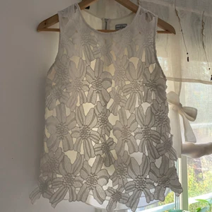 Blus - Fin blus med vita ”virkade” blommor fram och tyg bak. Dragkedja i ryggen. 