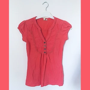 Rosa / Korallfärgad Tröja - Strl XS - Korallfärgad kortärmad tröja från 365 Sunshine i storlek XS. Är V-ringad med 4 knappar framtill.