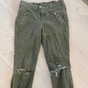 Guess byxor - Gröna guess byxor med hål på knäna och guldiga dragkedjor, stretchigt material, INGA FICKOR! Säljer billigt då jag köpte dom för ett tag sen, annars är dom i fint skick, jätte sköna