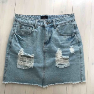  - Snygg kort jeanskjol med slitningar. Från Nelly.com och knappt använd. Den perfekta jeanskjolen!