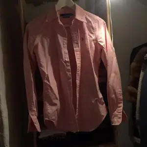 Ralph Lauren skjorta i rosa köpt på NK i stockholm för 2 år sedan. Använd ca 3/4 gånger. Inga slitningar eller fläckar. Helt i nyskick. Säljes pågrund av stilbyte. Jag fick den i present men jag tror nypris ligger på 1300. Kan mötas upp i city eller skickas