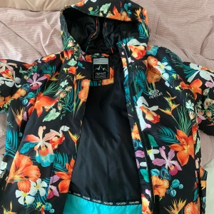 Cool skidjacka från Ripcurl - Säljer min ascoola skidjacka från RipCurl som tyvärr inte kommer till användning längre. Perfekt till den som vill vara snygg och synas i backen!! Har verkligen älskat denna jackan och den har hållt mig varm under vintern. Mycket fint skick och bra kvalite! Har snölås och en luva som funkar att dra över hjälmen. Även liftkortsficka på vänster arm och innerfickor som du tex kan ha telefonen i. Jag köpte den på SkiStar för 1200kr nypris för va två vintrar sedan.