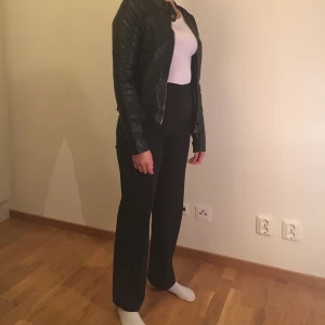 Skinnjacka  - Svart skinnjacka. Fake skinn. Finns även luva till som kan skickas med. Tre fickor där fram. Passar S och kan även passa XS. 