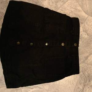 Nästintill oanvänd svart kjol med knappar framtill 