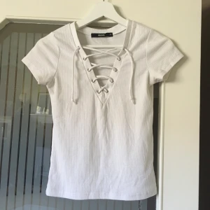 Snörad t-shirt - Vit ribbad t-shirt med snörning, storlek XS. Skön och stretchig! Knappt använd, jättefint skick! 