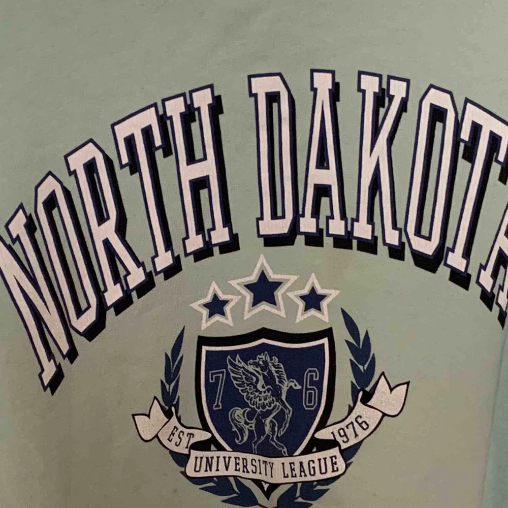 Jättesnygg mintgrön/blå sweatshirt med trycket ”North Dakota” från Gina. Bra skick men säljer då den aldrig kommer till användning. Storlek är xs men skulle nog säga att det är en S och även en M kan ha den. 💖 frakt tillkommer . Tröjor & Koftor.
