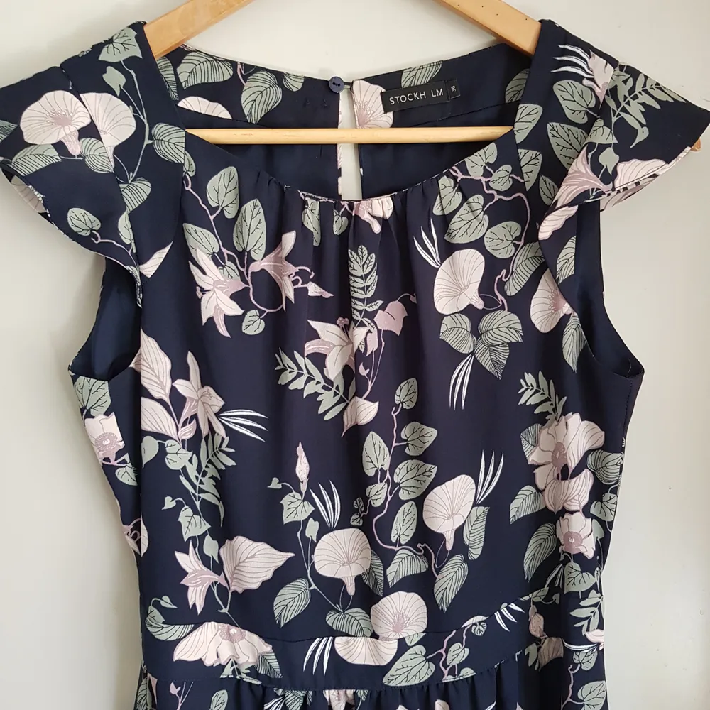 En otroligt fin klänning med blekt rosa blommor,ljust gröna blad på mörkblå botten. Köpt på MQ,märket STOCKH LM och endast använd vid ett tillfälle,superfin. Storlek 36. Klänningar.