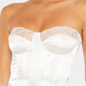 Vit korsettopp  - Jättesnygg, söt och sexig korsettopp i satin liknande material! Kan både användas till vardags och som en lite finare topp. Köptes på pretty little thing men säljs pga för liten. UK size 8 vilket motsvarar 36. Säljer den för 170 kr inkl frakt! 