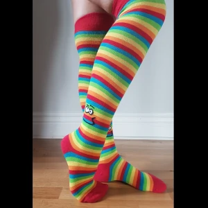 Regnbågsfärgade knästrumpor Happy Socks! - Regnbågsfärgade, lårhöga, knästrumpor med smileys, från Happy Socks! 🤩😃🌈🧦 Ena strumpan har antydan till två hål uppe i den röda tjocka "resåren" (skickar bild på förfrågan). 😊 Frakt tillkommer med 22 kr.