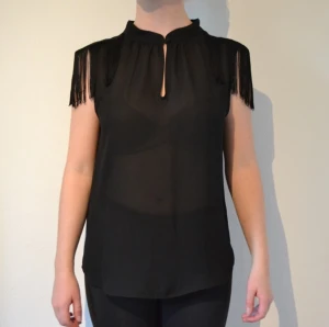  - Svart transparent topp med fransar på axlarna. Jag möts gärna upp i Stockholm eller skickar den på posten.
