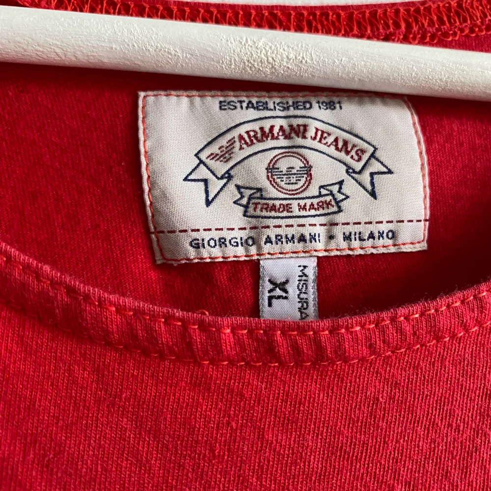 En röd Giorgio Armani t-shirt som jag köpte för några år sedan och som jag tyvärr inte använder idag. Tröjan är fortfarande i mycket gott skick och passar för de flesta tillfällen. Tröjan är i storlek XL men har passformen M. T-shirts.