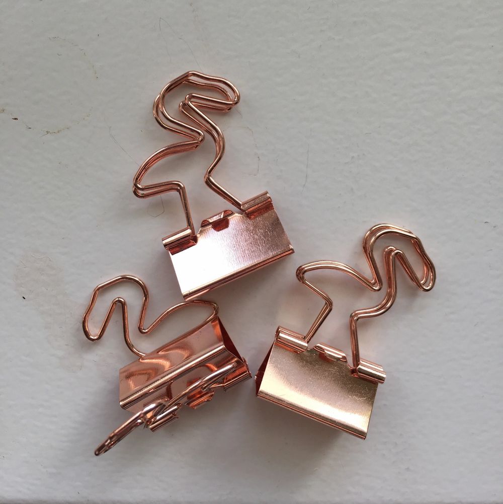 Klämmor i roséguld som ser ut som flamingos. Väldigt praktiska eftersom att de kan användas till allt. Samla ihop dina kvitton eller organisera viktiga papper eller häng upp en tavla med hjälp av dem. Jag använder inte just dessa. Därför säljer jag dem. . Accessoarer.