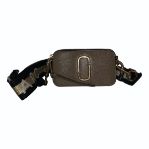 Marc Jacobs väska - Marc by marc Jacobs snapshot väska i beige/brun läder som har ett justerbart crossbody band. Knappt använd. Pris kan diskuteras men frakt tillkommer. Nypris 3750kr
