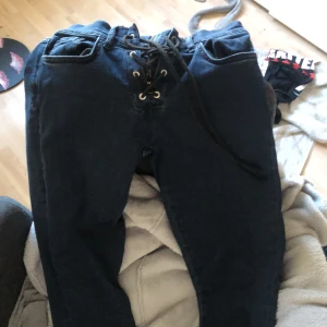 Unika jeans  - Säljer dessa mörkblå jeans för att de är för små för mig. De har snörning istället för knappar samt nere vid benen. I nyskick då jag köpte fel storlek. Liten i storleken, brukar ha S men de är aningen tighta på mig!