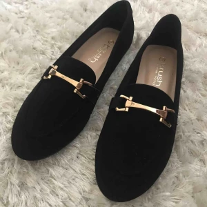  - Aldrig använda! Svarta ballerinaskor med guldsmycke, moccaimitation. 