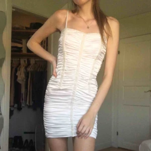  - En vit kort klänning i silkeaktikt material. Den sitter tajt med dragkedja på sidan och justerbara band. Själv tänker jag att man kan göra nån halloweencostume av den. ~Frakt(36kr) ingår i priset