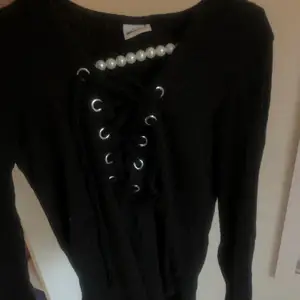 En svart tröja i storlek S med band urringning.