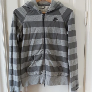 Nike hoodie - Grå randig hoodie med zip från Nike. Välanvänd så metalldelarna är lite slitna men inget man tänker på, kan skicka bild. Dragit ur snöret ur luvan. Cool liten ficka i högerfickan.
