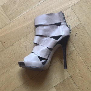 Högklackade skor  - Högklackade skor i ljust läder. Klacken är mörkbrun och 12 cm hög. Knappt använda. 