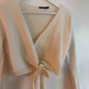  - Cremevit stickad tröja med långa ärmar & knytband fram.