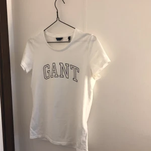 GANT white T-shirt  - Vit gant T-shirt. Nyskick. Säljs pga använder ej. Blå gant text. Köpt i våras och använd vid fåtal tillfällen. Känns som ny i kvaliten. 