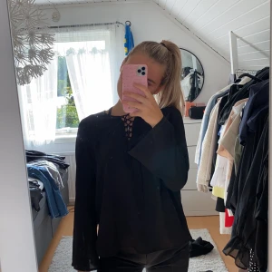 Svart blus - Svart blus med snörning fram. Lös passform storlek 34. 