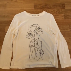 Vit Långärmad med kvinnoanikte  - Säljer denna fina långärmade tröjan med ett streckmålat kvinnoansikte från Nelly.com💗💗bara använd 1 gång och säljer den för att jag hade velat ha den i en större storlek. Köparen står för frakt🥰