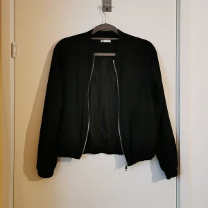 Cubus svart bomberjacka strl S - Svart tunnare bomberjacka med dragkedja i silver. Strl S men passar även strl M i mer figurnära passform. 100% polyester. 