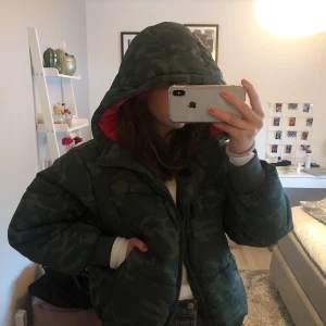 Jacka Dun - Asball dunjacka, super varm och gosig!! Camo färg + röd insida! Går att spänna till/släppa upp i midjan beroende på vilken passform man vill att den ska ha! Storlek M! Frakt ingår ej🥰💕
