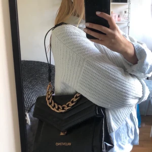 Valentino väska - Svart väska med gulddetaljer från valentino by Mario Valentino. köpt här på plick. Dustbag medföljer. Köparen står för frakten. Frakten är inkluderad.