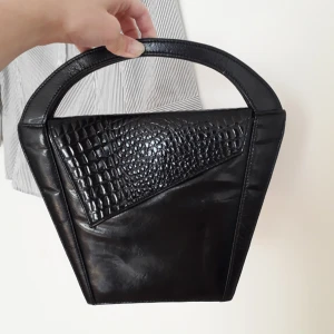  - Ursnygg och ovanlig vintage väska köpt secondhand! Denna blir du nog ensam om! Krokopräglad upptill och lite lackerad i sin svarta färg!🌼Ett lite ljusare fläck/parti på baksidan(se bild)pga sitt vintageskick, fast gör den bara charmigare i allt! Frakt: 54:-