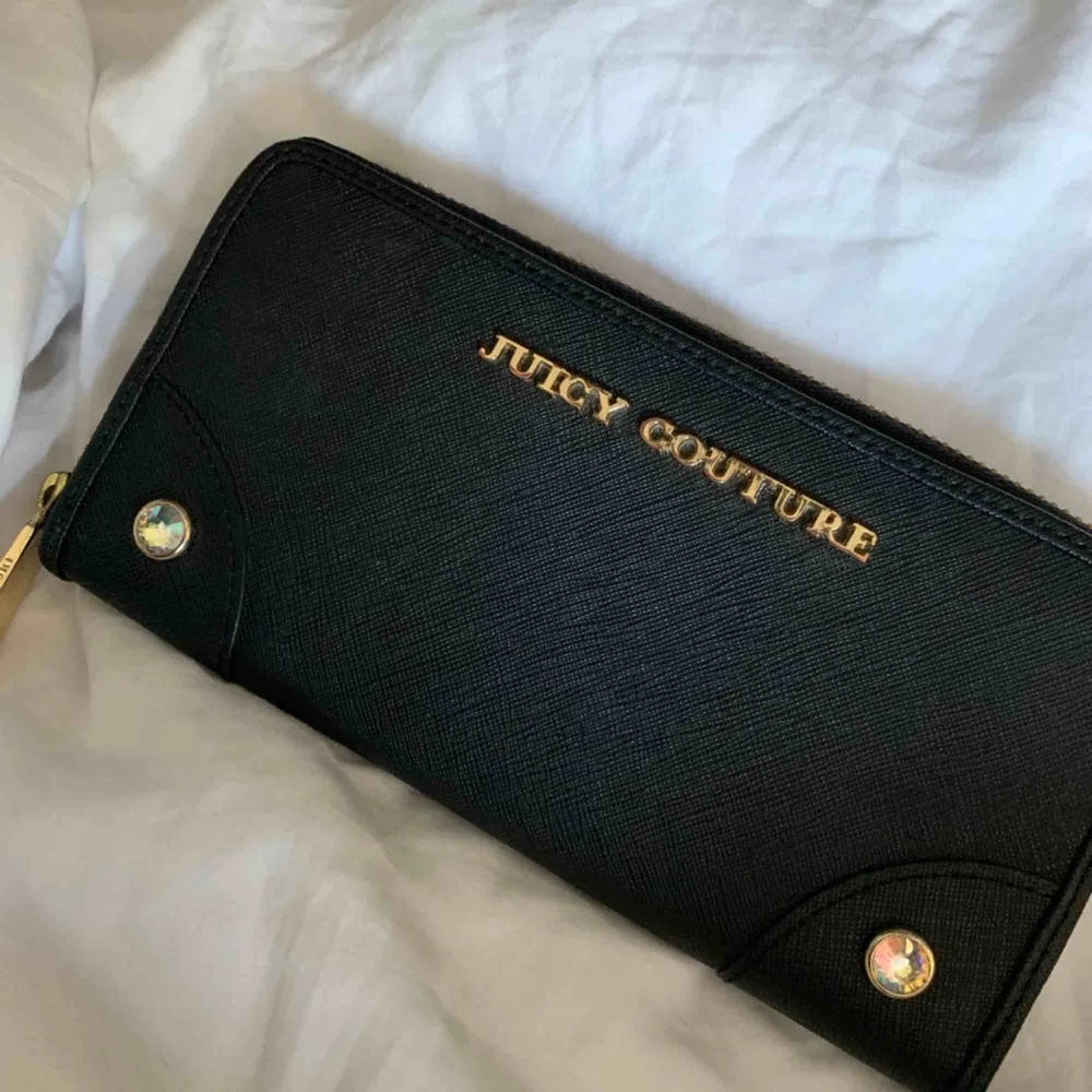 Äkta Juicy couture plånbok köpt i NYC. Fins skick, knappt använd bara legat i en låda i flera år. Finns en liten fläck på baksidan men den är knappt synlig (finns bild). Orginalpris är 800kr  Priset kan sänkas vid snabb affär. Väskor.