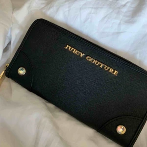  - Äkta Juicy couture plånbok köpt i NYC. Fins skick, knappt använd bara legat i en låda i flera år. Finns en liten fläck på baksidan men den är knappt synlig (finns bild). Orginalpris är 800kr  Priset kan sänkas vid snabb affär