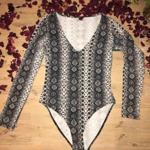 body i strl. S - en snygg åtsittande body i ormmönster och med djup urringning, fint skick!! frakt tillkommer