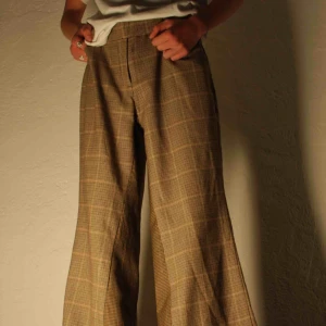  - Ett bar breda kostymbyxor som är stilrena med rutigt tryck