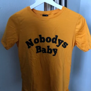 T-shirt nobodys baby - Senapsgul t-shirt från Gina tricot, skön lös passform och knappt använd✨✨ Storlek XS