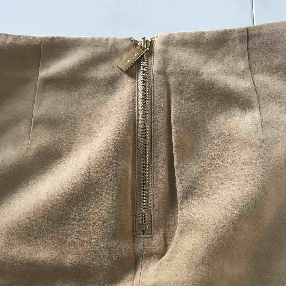 Beige omlott-kjol från IVYREVEL med gulddetaljer. I mycket bra skick, aldrig använd. Tyget liknar velvet och dragkedja baktill. Vid köp tillkommer fraktkostnad.. Kjolar.