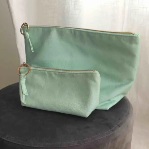  - 1 större och 1 mindre necessär i ljus turkos. Fint skick utvändigt men märken från smink invändigt i den lilla framför allt (har tvättats men går inte bort). Jättefina, hela och fräscha! Använts till smink och nagellack. 