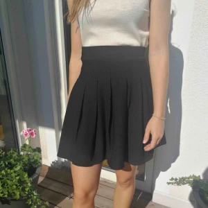  - Svart veckad kjol med slits. Aldrig använd 