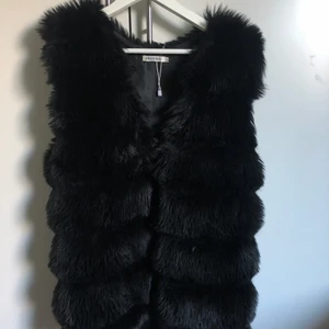 Svart väst i fuskpäls från tessie, strl m-l - Svart väst i fuskpäls från tessie, Cherry Koko, i storlek m-l. Passar även mig som vanligtvis har strl S. Nypris: ca 500 kr. Jag säljer västen för 70 kr plus frakt, alltså 133 kr. Använd endast ett fåtal gånger. Kan skicka fler bilder vid intresse. En krok som man har för att stänga jackan med har gått av vilket gör att den inte går att knäppa, priset kan därför diskuteras.