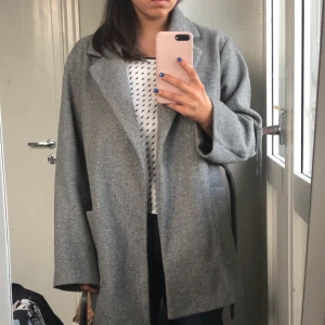 Grå kappa zara - Grå kappa mid längde med inbyggt skärp från zara. Storlek M, vintage lite oversize passform. Köpt förra vintern använder inte längre därför jag säljer. Köpt för 400kr. Frakt 70/ möts upp