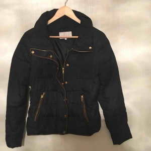  - En kort svart jacka med en brun bord