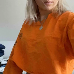 - Orange långärmad med tryck på armarna och bröstet, storlekslappen är borta men jag är en xs