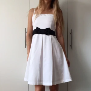  - Klänning från Zoul, MQ, storlek 34. Superfin till studenten eller sommarfesten. Endast använd 1 gång, som ny. Vit med svart band samt rosett framtill, reglerbara axelband. 