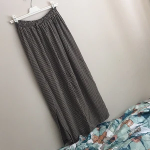  - Superfin långkjol med slits i sidan. Hällor för skärp. Randig i svart och mörkt beige. Passar allt från S-L. Kanske även XS. Resår i midjan. Oerhört fin till en blus/ett linne och smalt skärp.