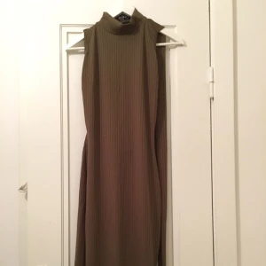  - Snygg midiklänning, militärgrön. Bar rygg med ett band som kan knytas på många olika sätt, slits på sidan. Oanvänd 